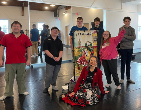 Miss Coco seated on floor, with students from a private nonpublic specialized day school gathered around after a Flamenco dance workshop